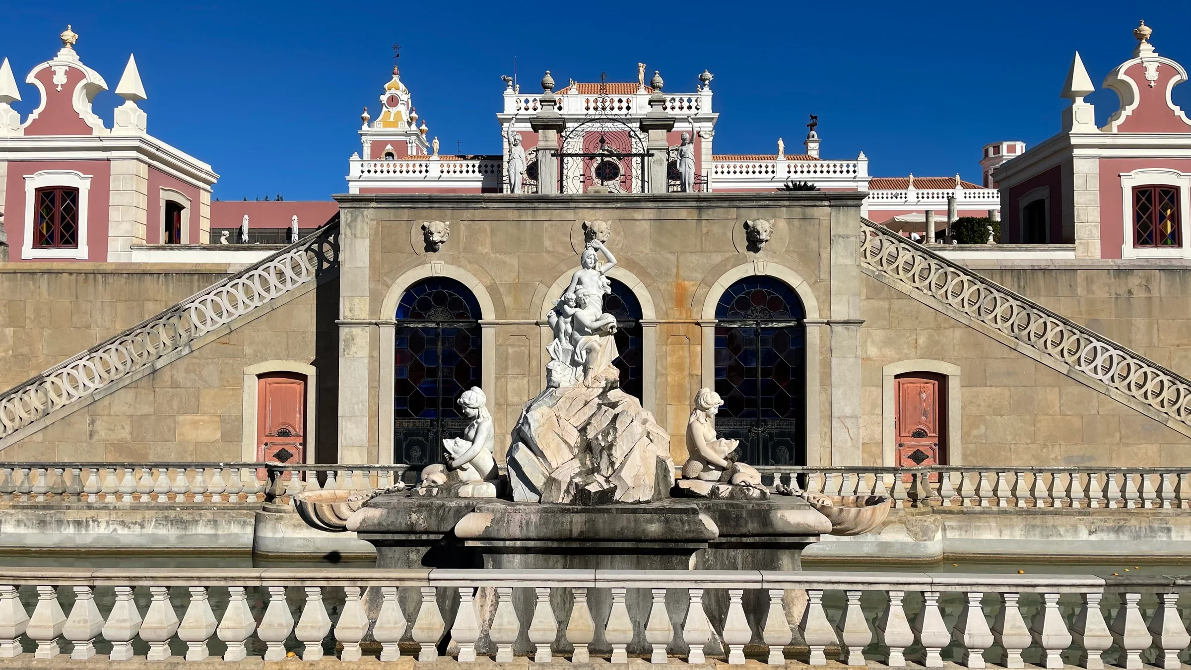 Formal gardens and fountain in front of the pink Palace of Estoi