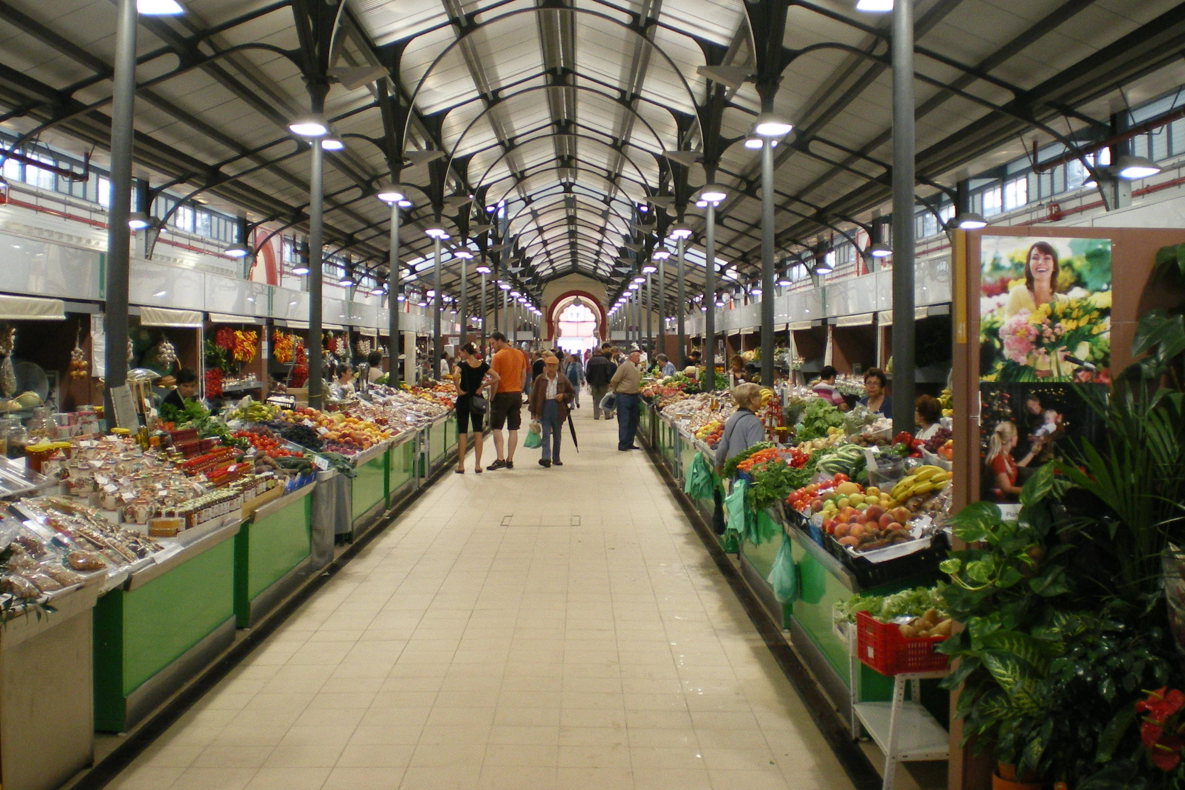 Inside Loulé Municipal Market, with colourful produce stalls, shoppers and iron arches