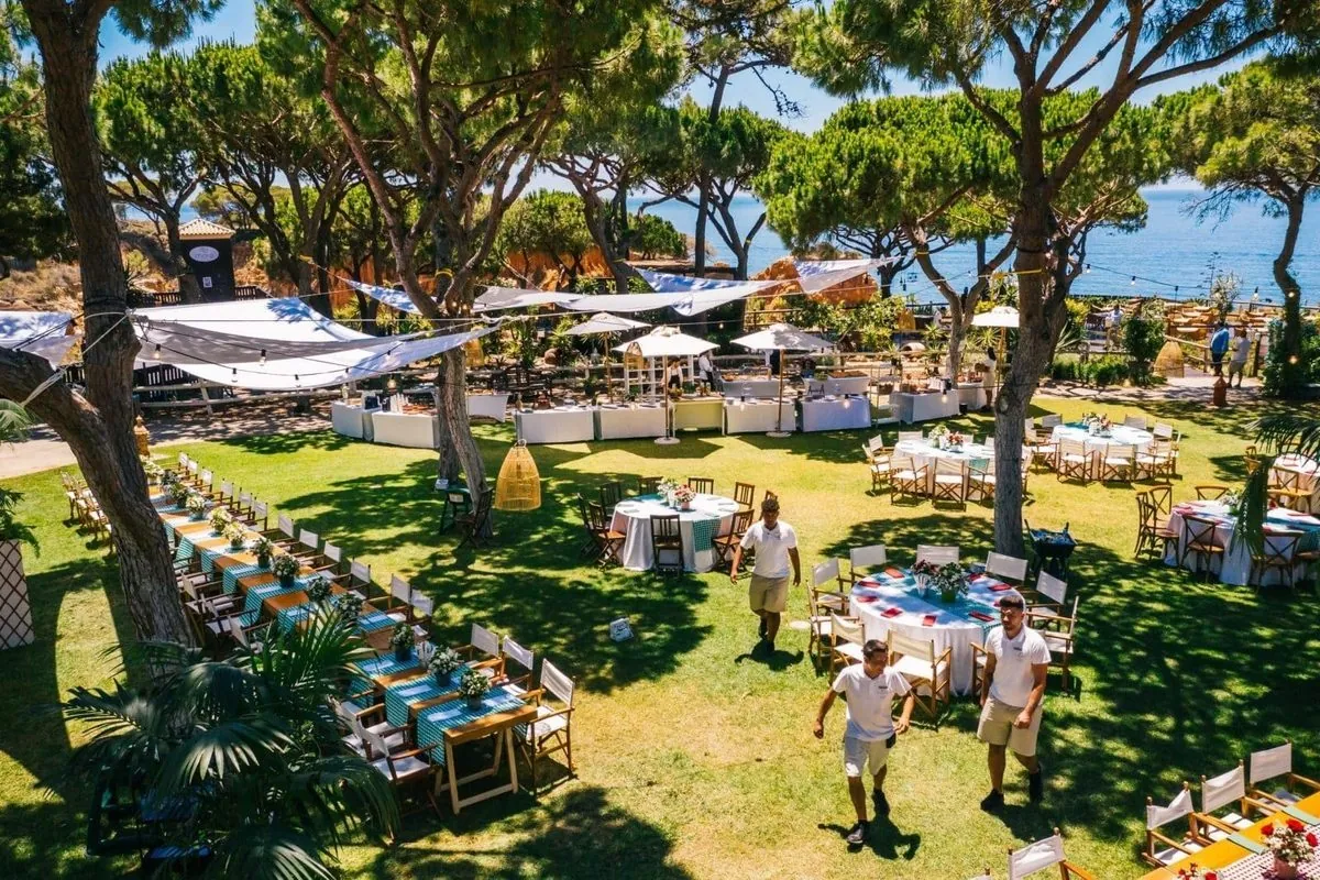Outdoor event tables arranged under pine trees at Pine Cliffs Resort.