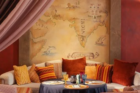 Rohini dining room with cushioned seating and an illustrated wall.
