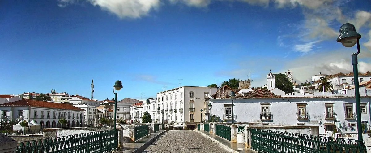 Tavira’s old bridge over the river, with white buildings along the waterfront.