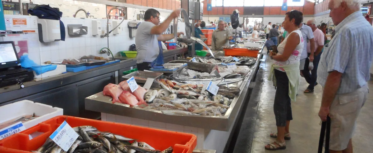 Fish stalls and people inside Olhão’s working fish market.