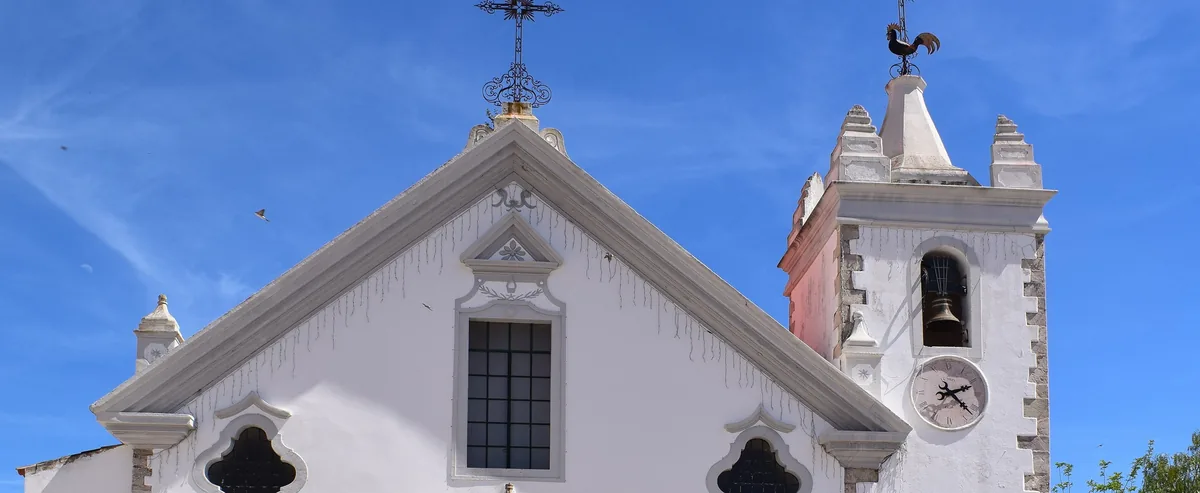 The parish church in Alte, with its white façade against blue sky.