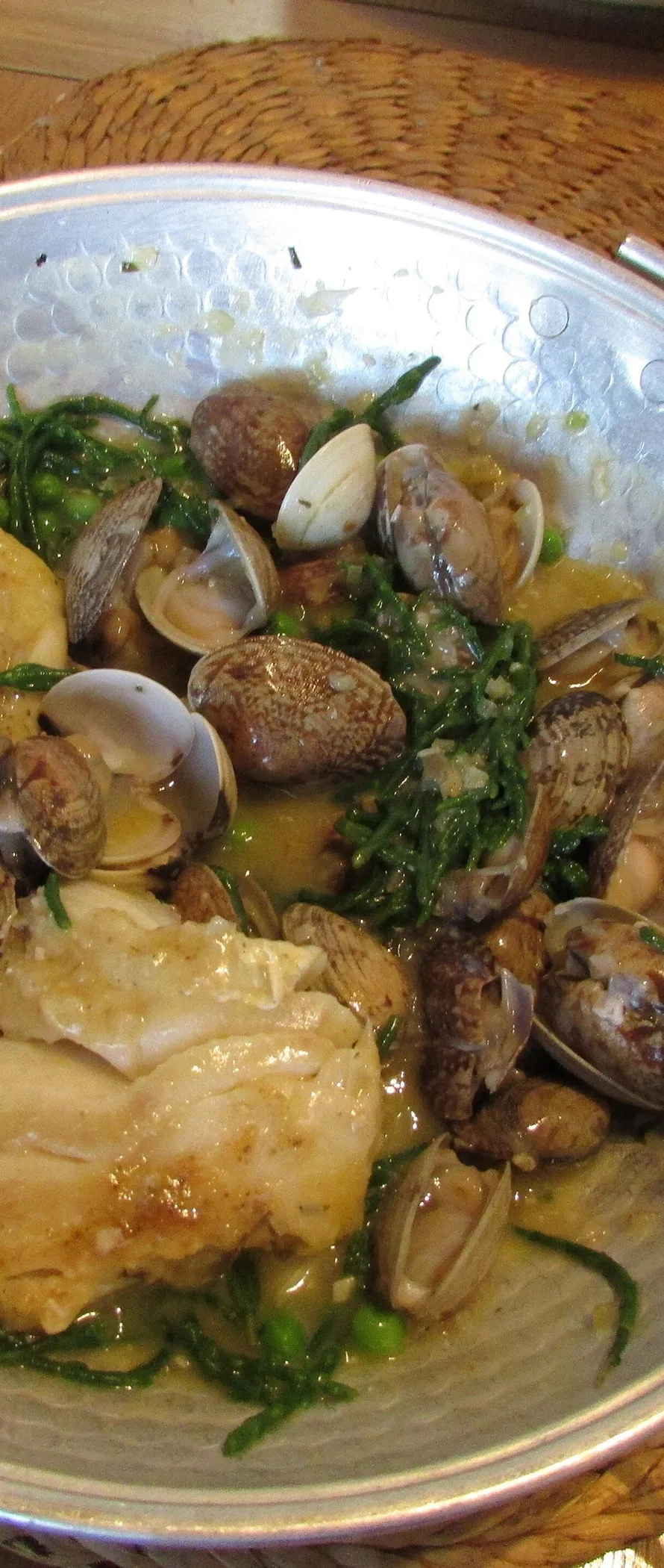 A seafood cataplana with shellfish and vegetables in its open copper cooking vessel.
