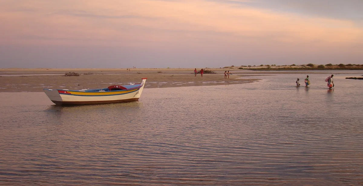 A small fishing boat in the shallow lagoon at Cacela Velha at sunset.