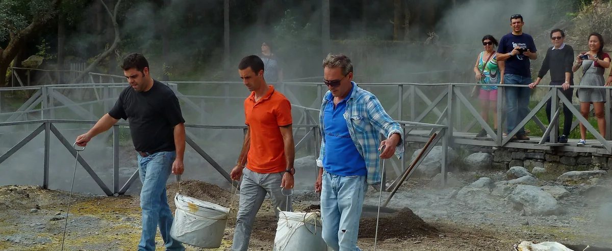 People carrying a cooking pot at the geothermal cozido area beside Lagoa das Furnas.