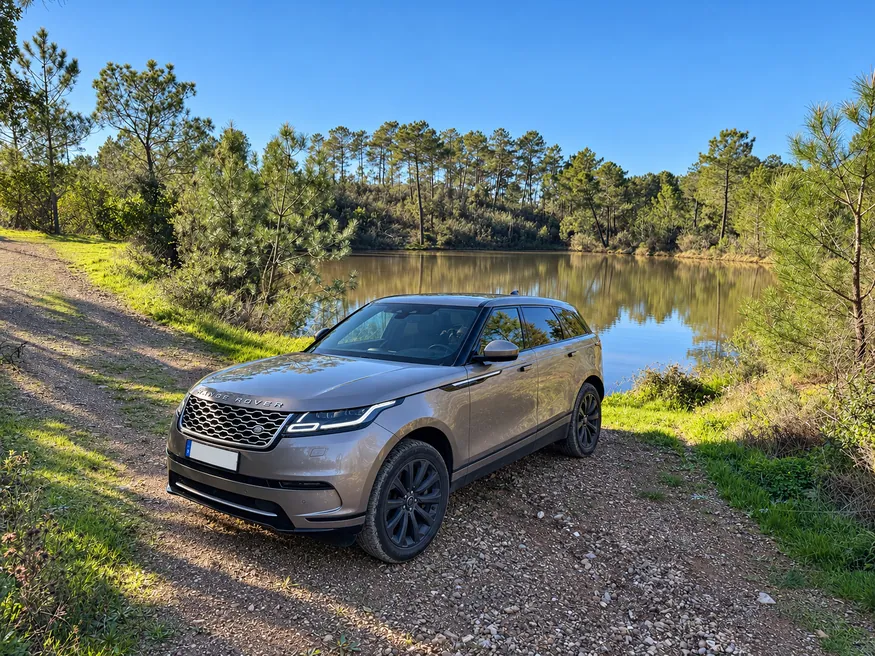 Range Rover Velar parked on a country track beside a small lake.