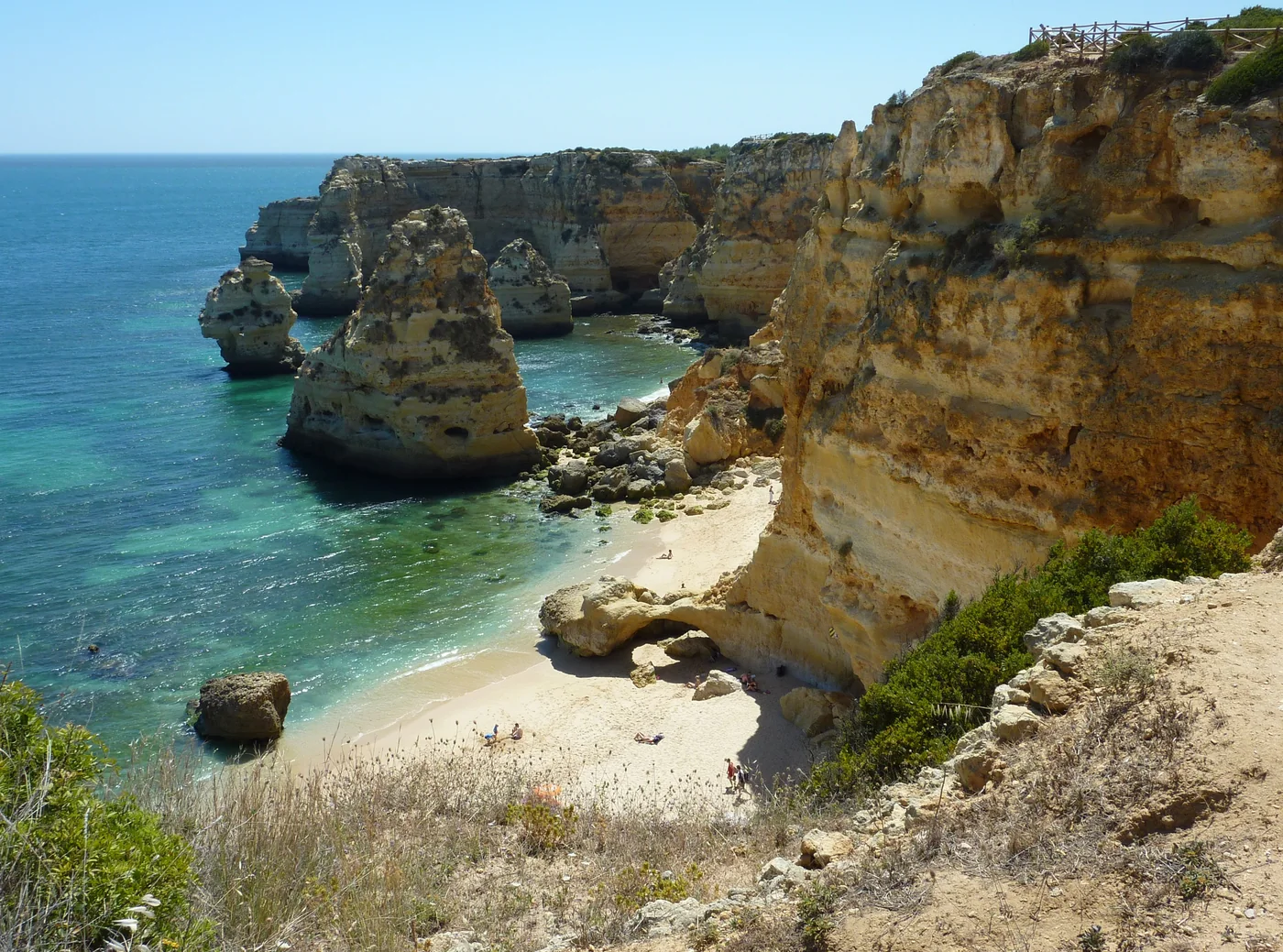 An Algarve cove with golden cliffs, a beach and turquoise water.