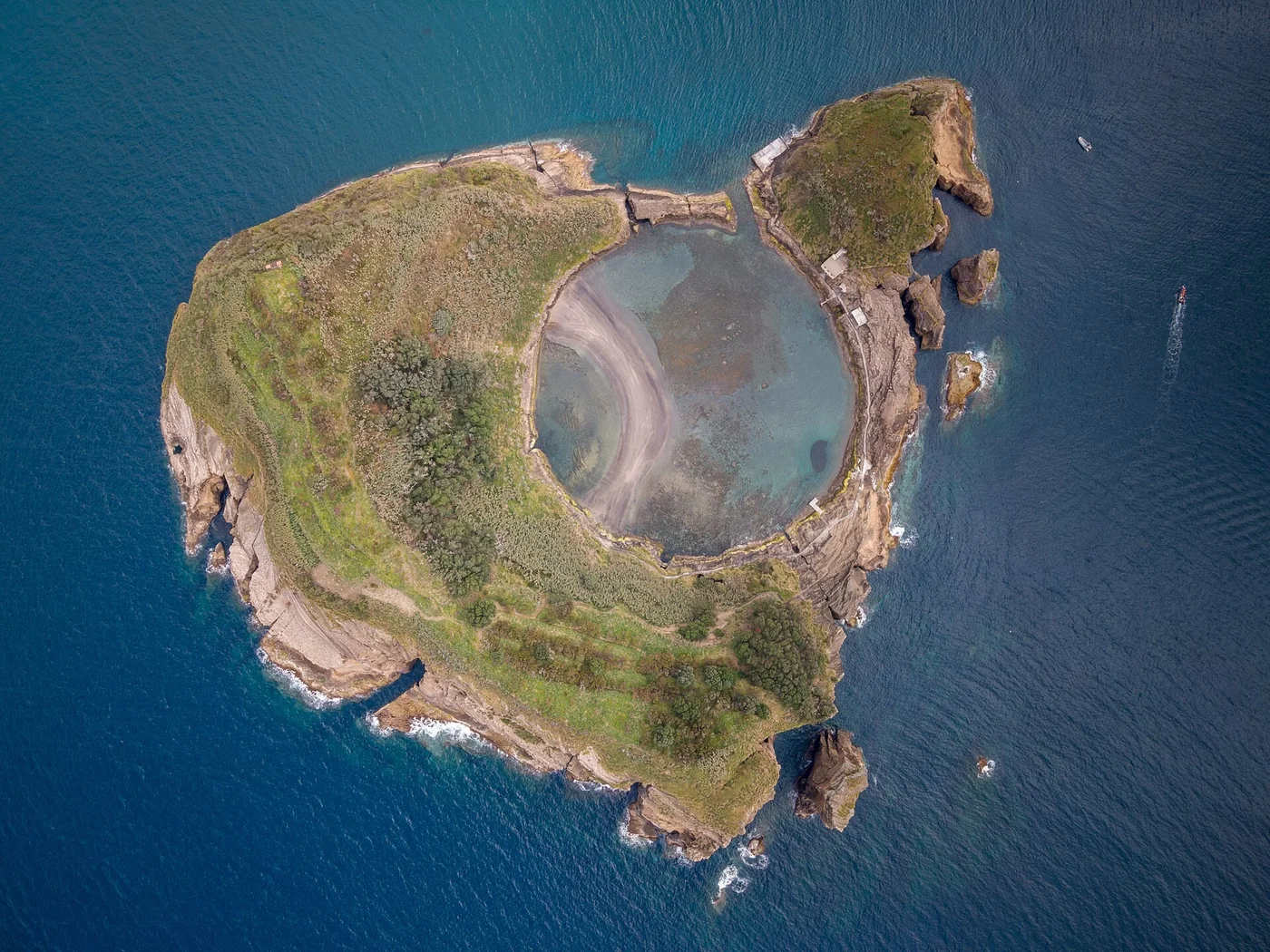 An aerial view of the circular lagoon and rocky coast of Vila Franca do Campo islet.